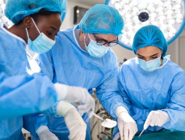 Équipe de chirurgiens en uniforme effectue une opération sur un patient dans une clinique