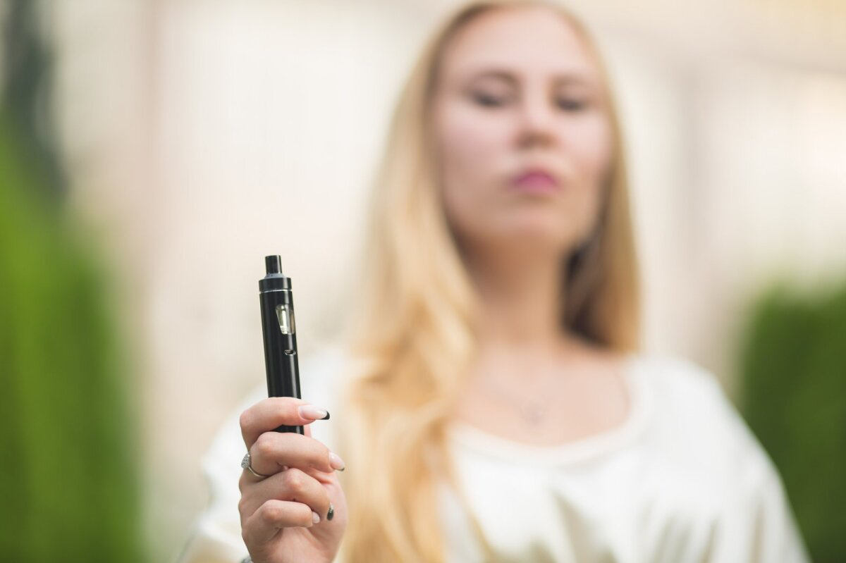Jeune femme qui tient une e-cigarette dans la main