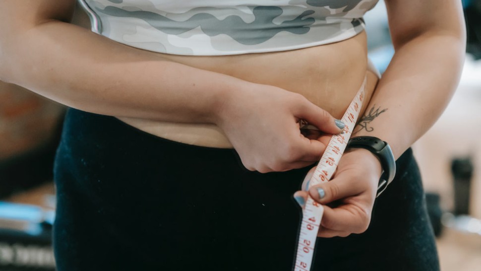 Young woman measuring her waistline