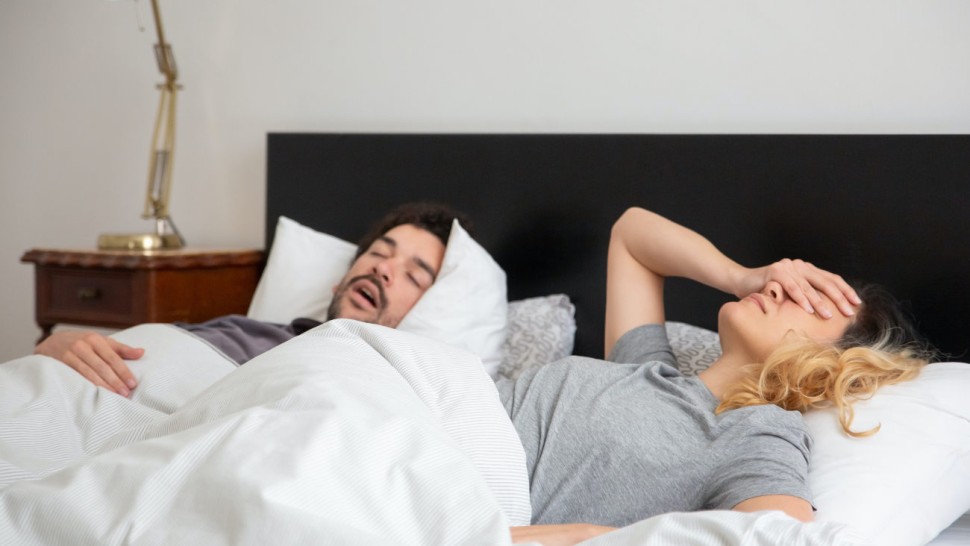 Homme qui ronfle au lit à côté de sa femme