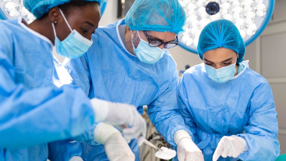 Équipe de chirurgiens en uniforme effectue une opération sur un patient dans une clinique