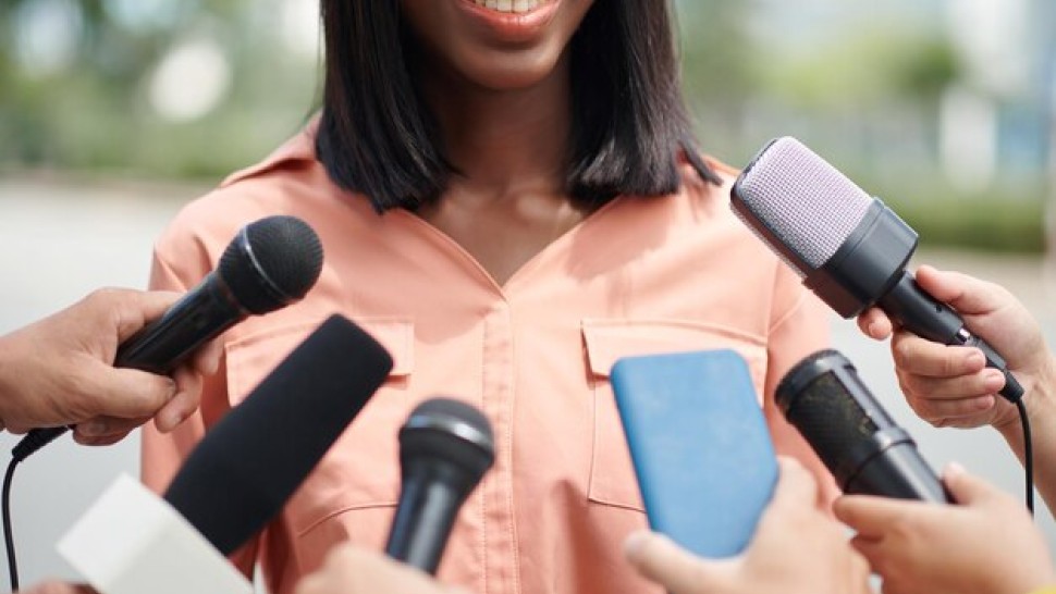 Une femme noire souriante parlant devant un micro