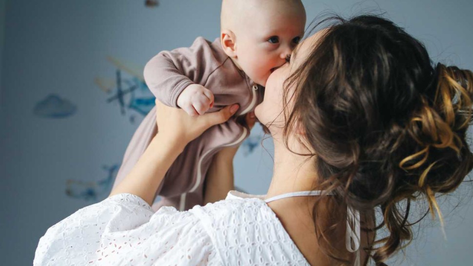 Une jeune maman qui porte son bébé