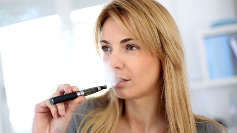 Jeune femme qui vapote une e-cigarette