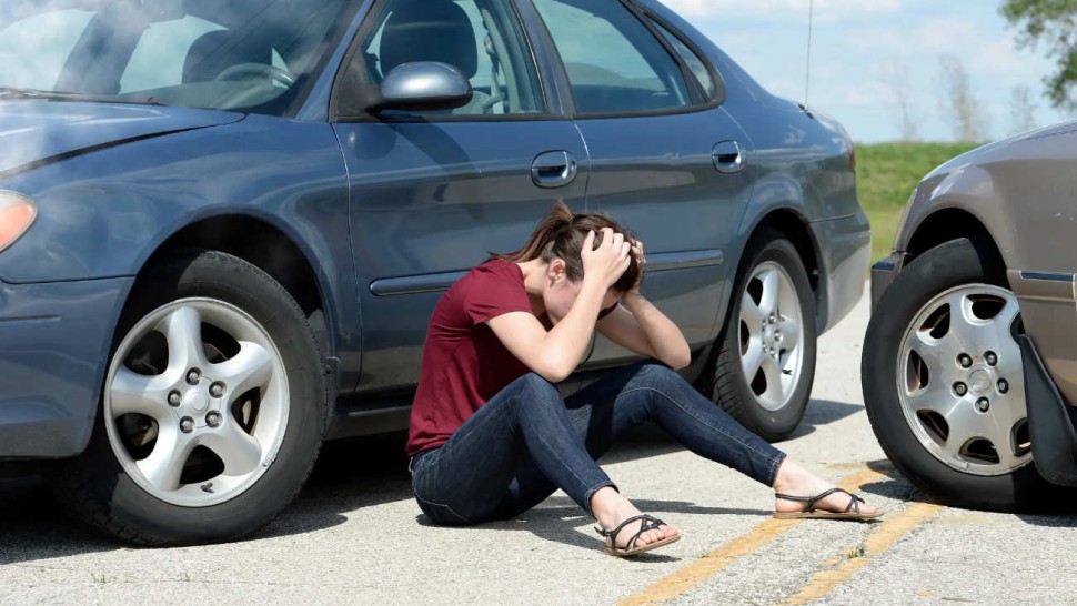 jeune assise sur la route après un accident