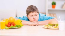 Jeune garçon obèse qui regarde de la nourriture sur une table