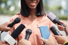 Une femme noire souriante parlant devant un micro