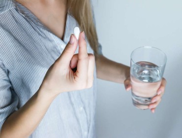 Femme qui consomme un complément alimentaire avec un verre d'eau