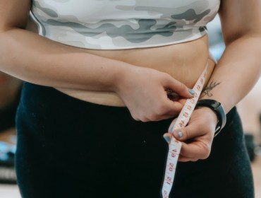 Young woman measuring her waistline