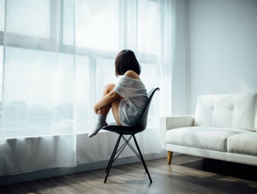 Jeune femme seule devant une baie vitrée