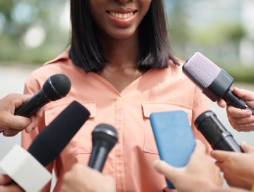 Une femme noire souriante parlant devant un micro
