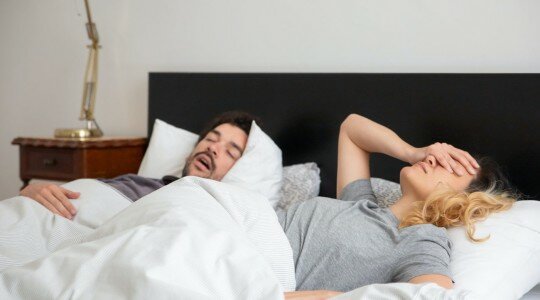 Homme qui ronfle au lit à côté de sa femme