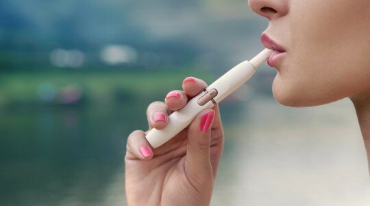 Une femme utilisant un dispositif de tabac à chauffer