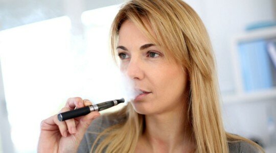 Jeune femme qui vapote une e-cigarette
