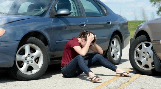 jeune assise sur la route après un accident